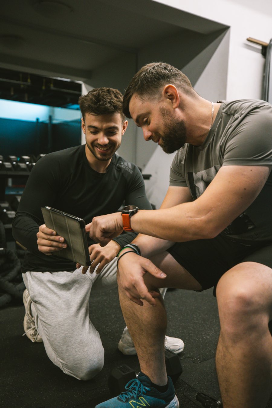 Trener personalny Jan Tekieli omawia plan treningowy z klientem na tablecie w studiu w Krakowie