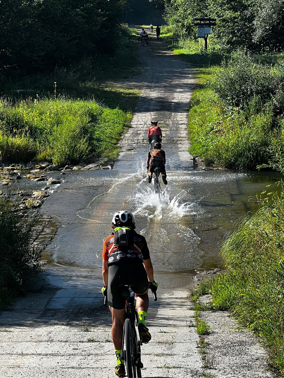 Kolarze przejeżdżający przez bród na trasie Poland Gravel Race