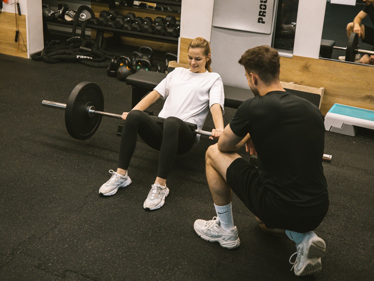Trening personalny w studiu treningowym z trenerem i klientką